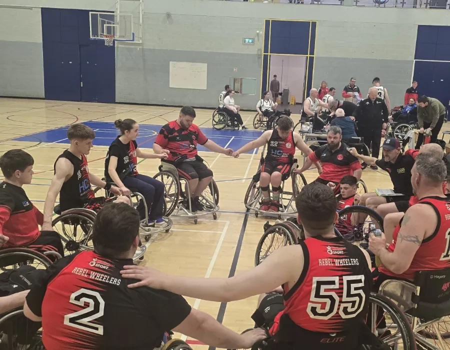 Senior wheelchair basketball players on court in a group huddle