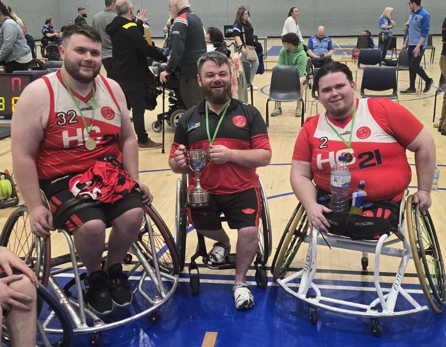 wheelchair basketball players posing with medals and trophy